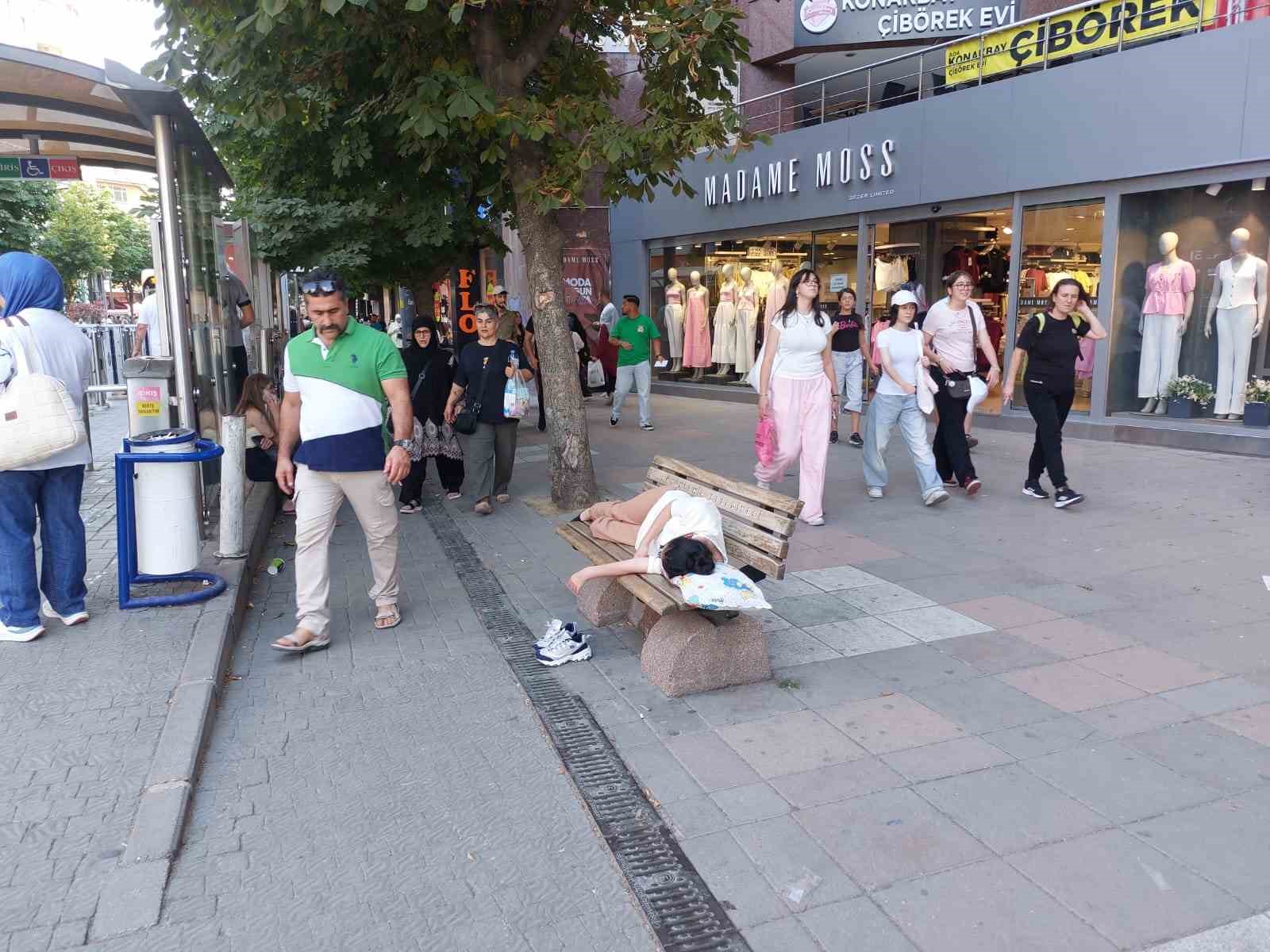 Sıcaktan bunalan genç gölgelik bankta yastıkla beraber uyudu
